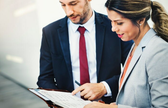 a woman and man standing and negotiating a contract together